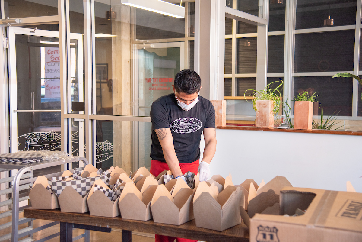 Worker with mask sets up lunches for Food for Our Front Lines initiative.