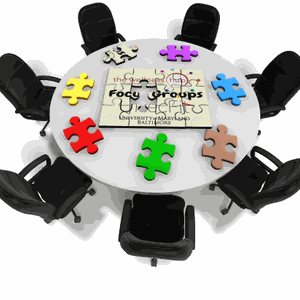 Chairs around a table holding puzzle pieces that make up the words focus group