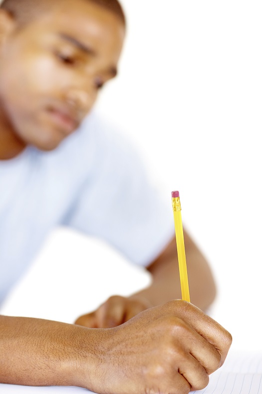 A person writing on a piece of paper with a pencil in their hand.