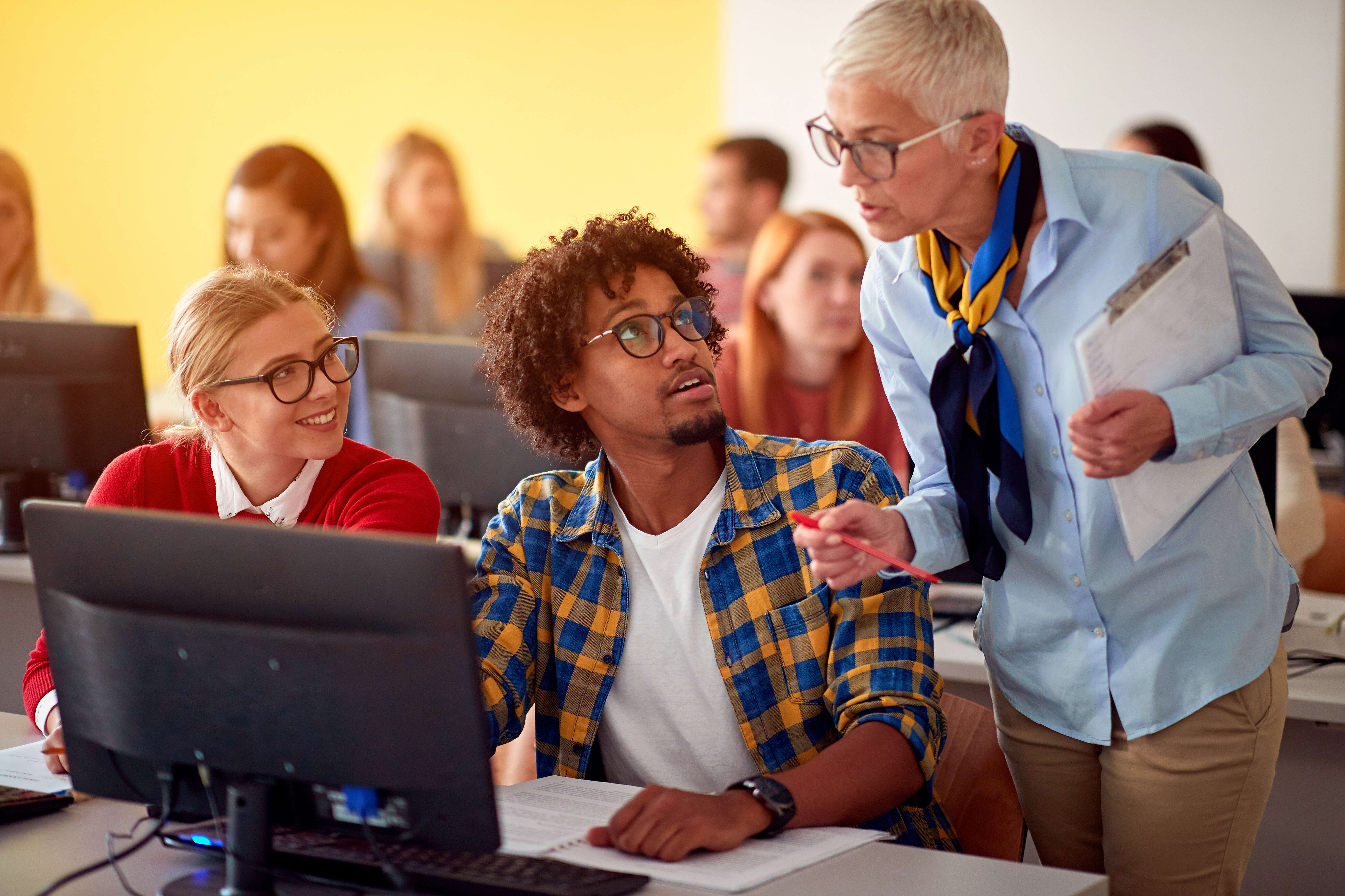 teacher leaning over student on laptop