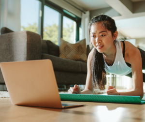 woman exercising while looking at laptop