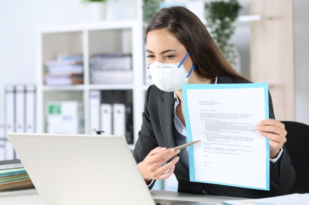 Executive with mask shows contract during video conference