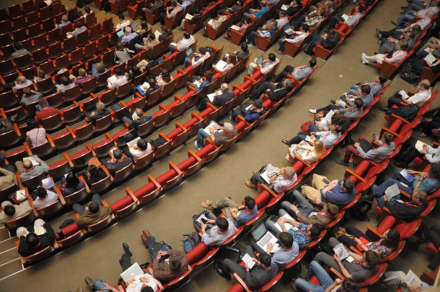 Lecture hall peppered with audience members listening to a conference.