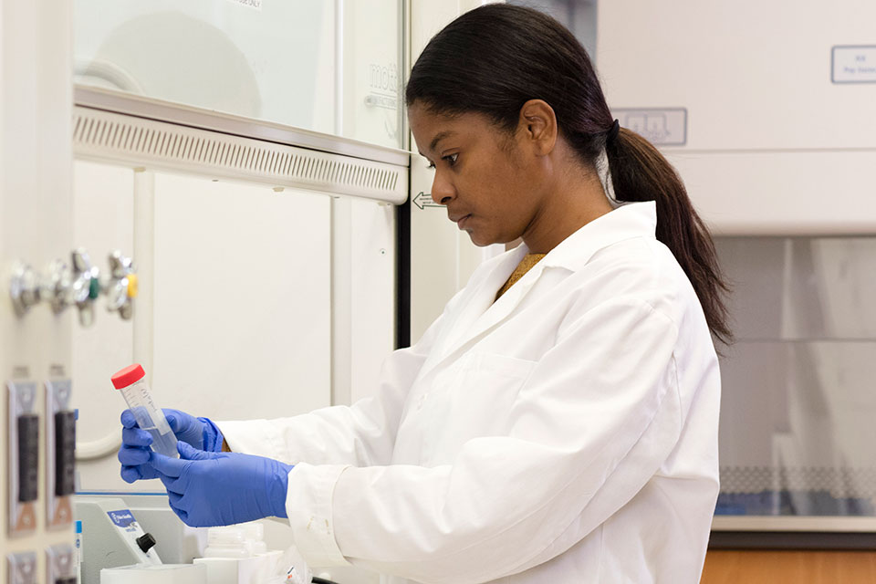 Graduate student in the lab analyzing test tube filled with clear liquid.