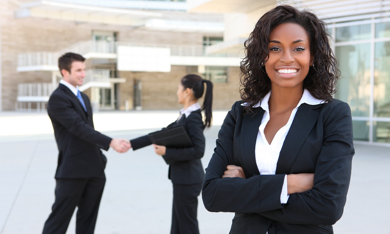 woman standing in the forefront with man and woman shaking hands in the background