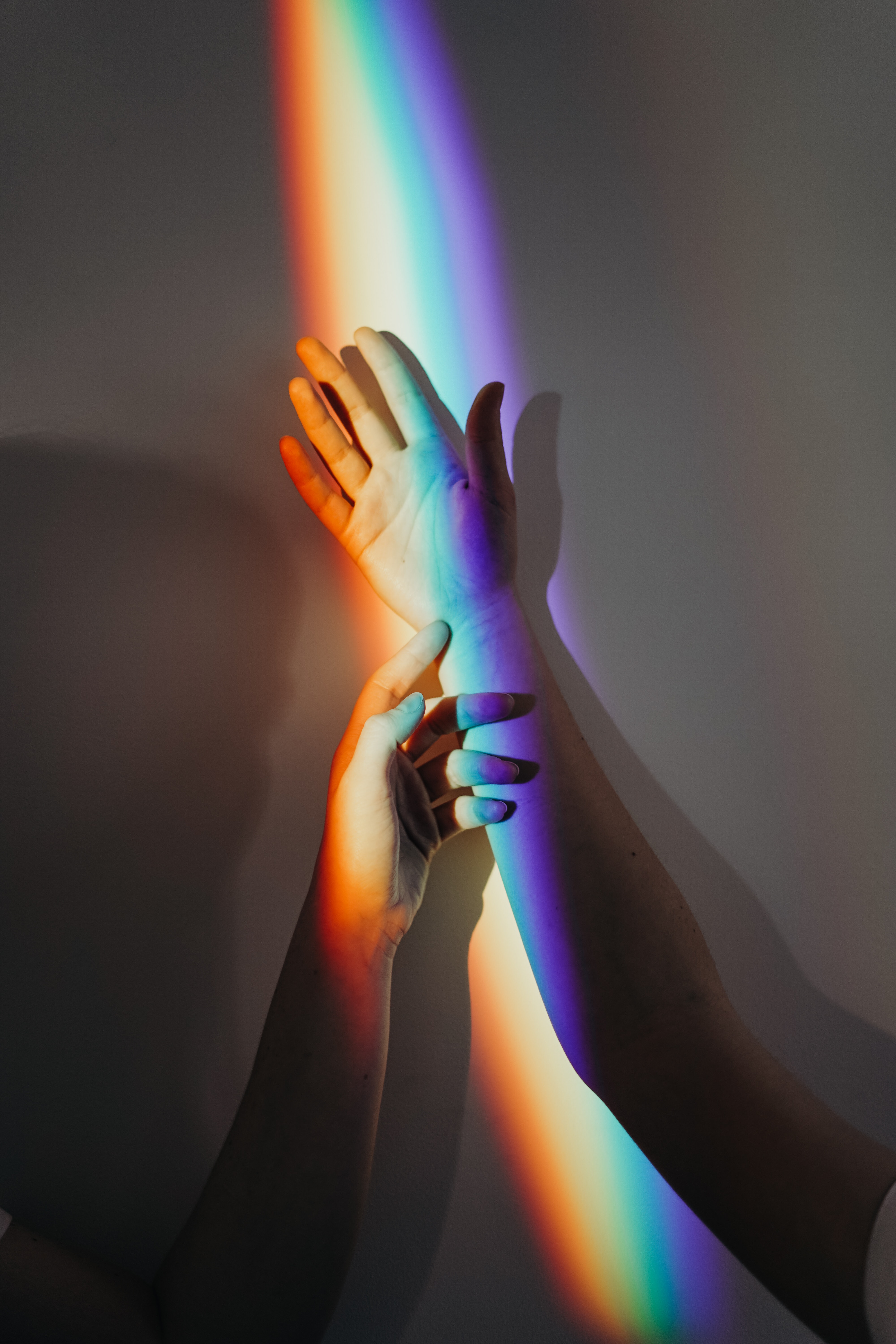 A rainbow light highlights two hands.