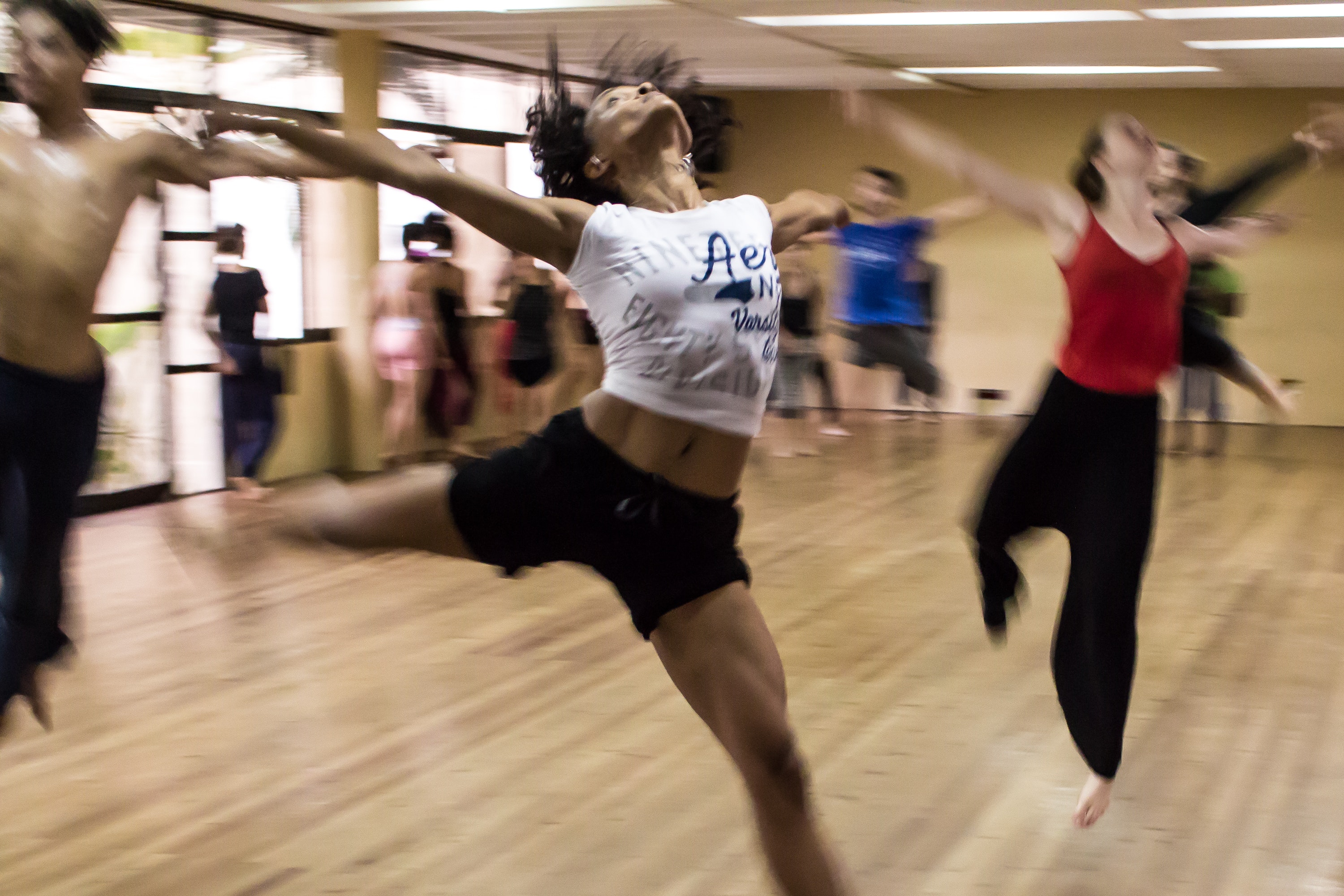 Individuals jump in mid air in a dance studio.