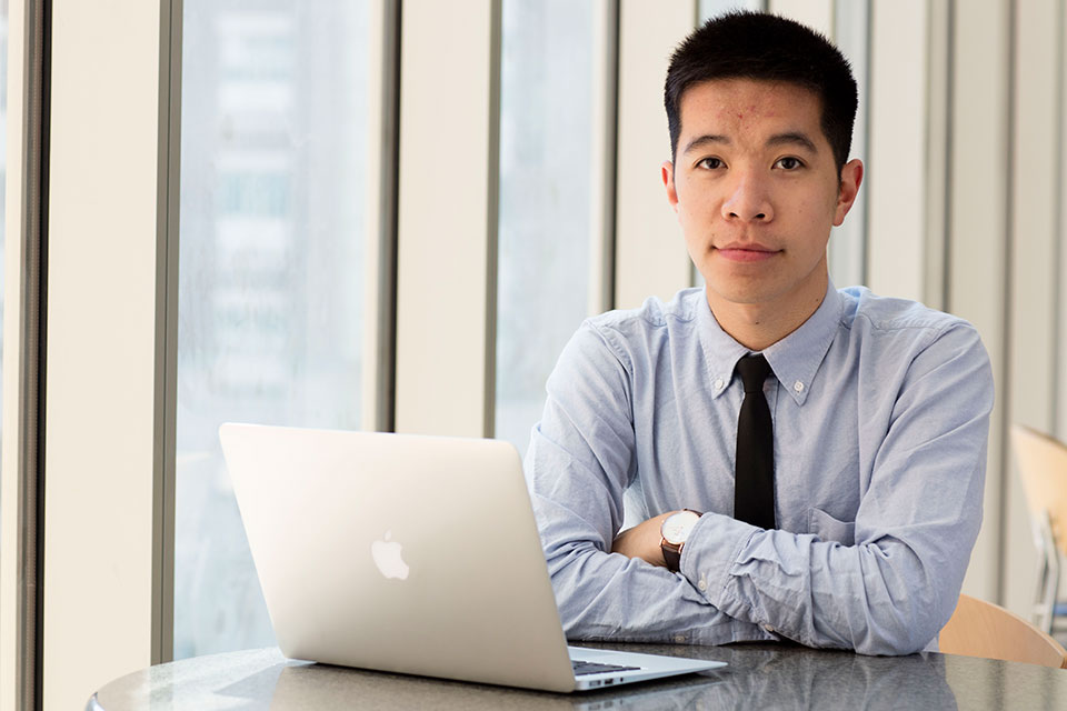 Student pharmacist seated at table with laptop.