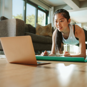 woman exercising on mat in front of laptop