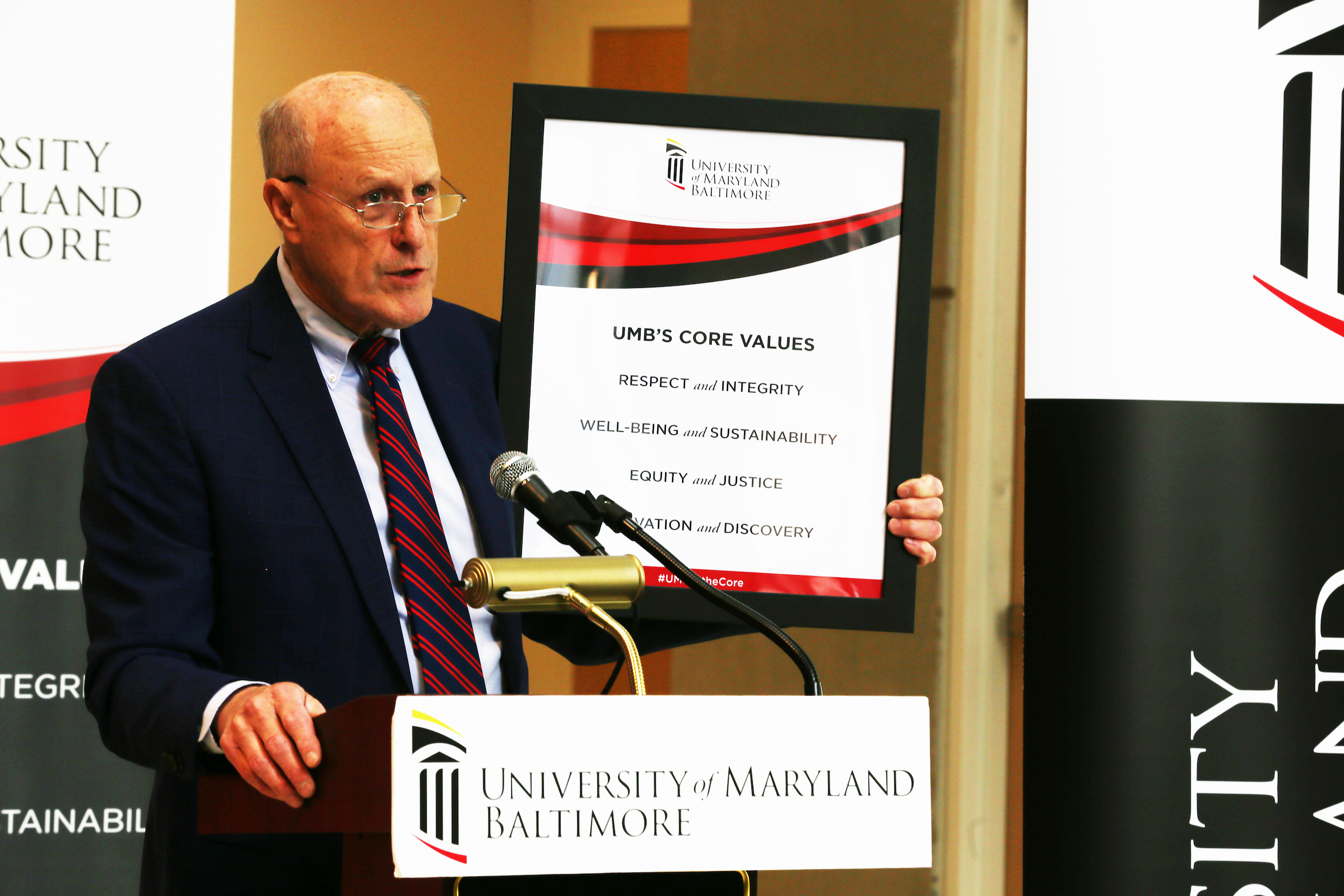 President Jarrell holds up a sign with the University's core values. 