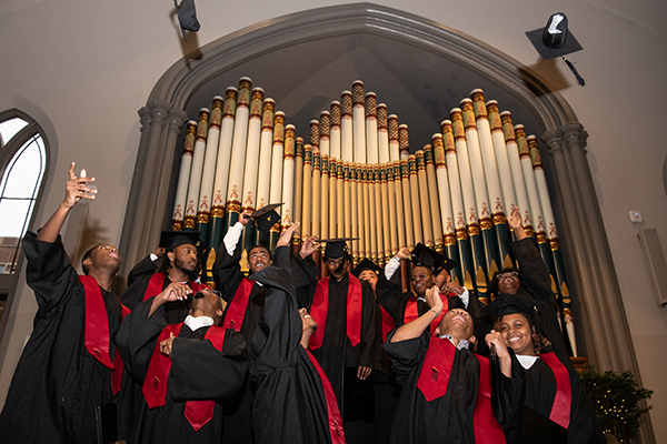CURE Scholars throw mortar boards in the air in front of the giant pipe organ in Westminster Hall