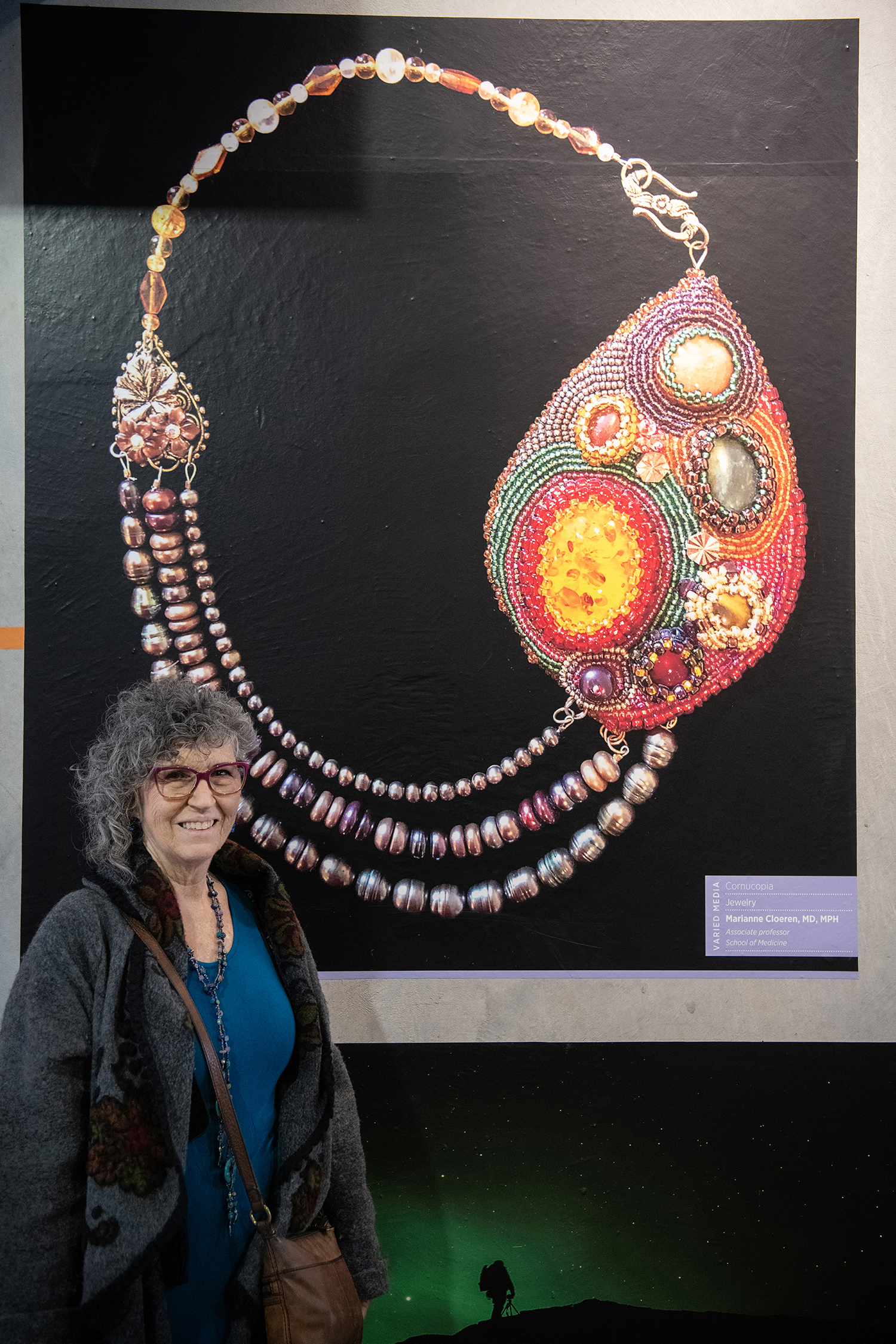 Marianne Cloeren stands in front of a photo of the asymmetric, handmade necklace she called “Cornucopia.”