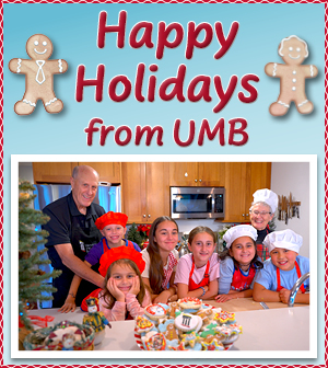 Happy Holidays from UMB with gingerbread men in graphic and a photo of Dr. Jarrell in the kitchen with his wife and grandchildren and a plate of cookies on the counter