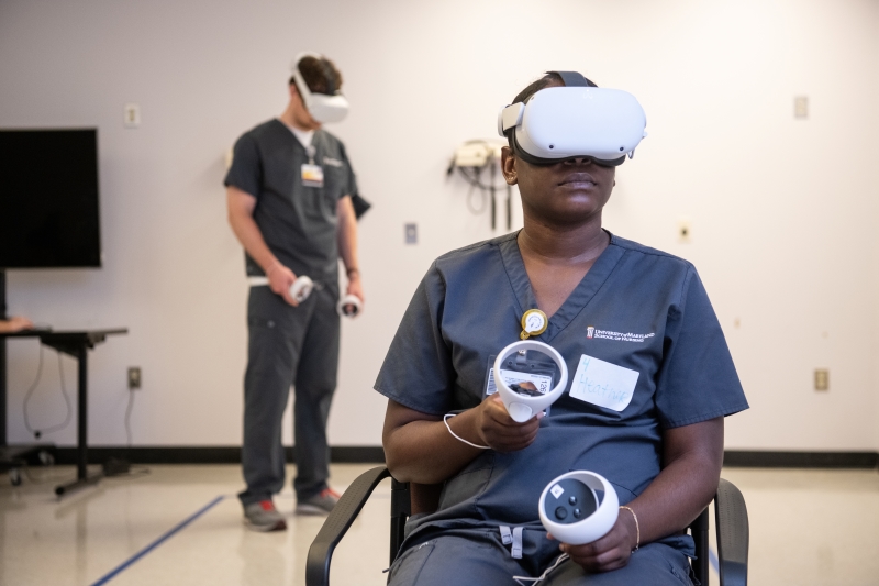 students in gray scrubs wearing VR headsets and holding controllers