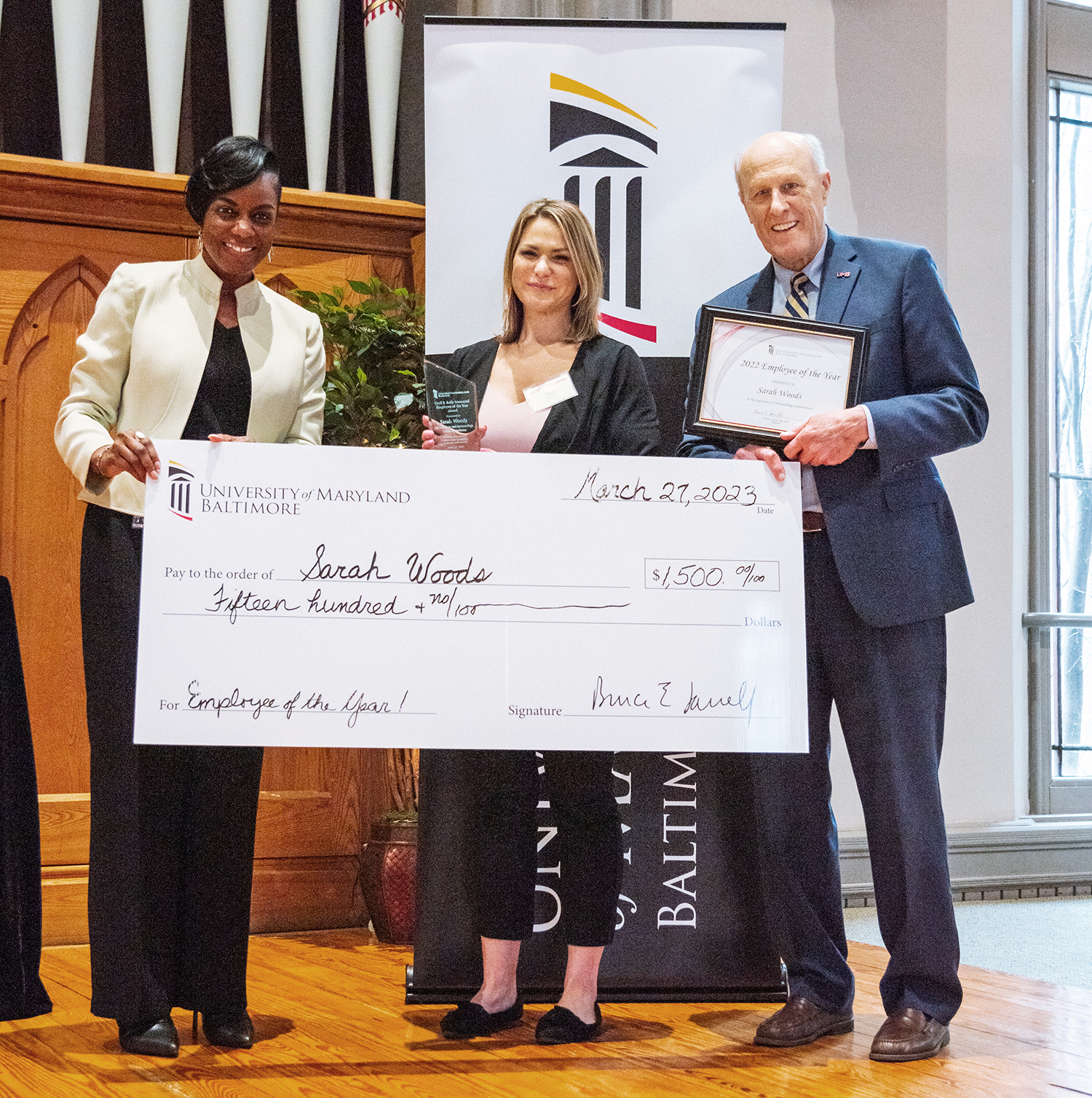 Sarah Woods, center, poses with UMB Chief Human Resources Officer Malika Monger and President Bruce Jarrell after being named Employee of the Year.