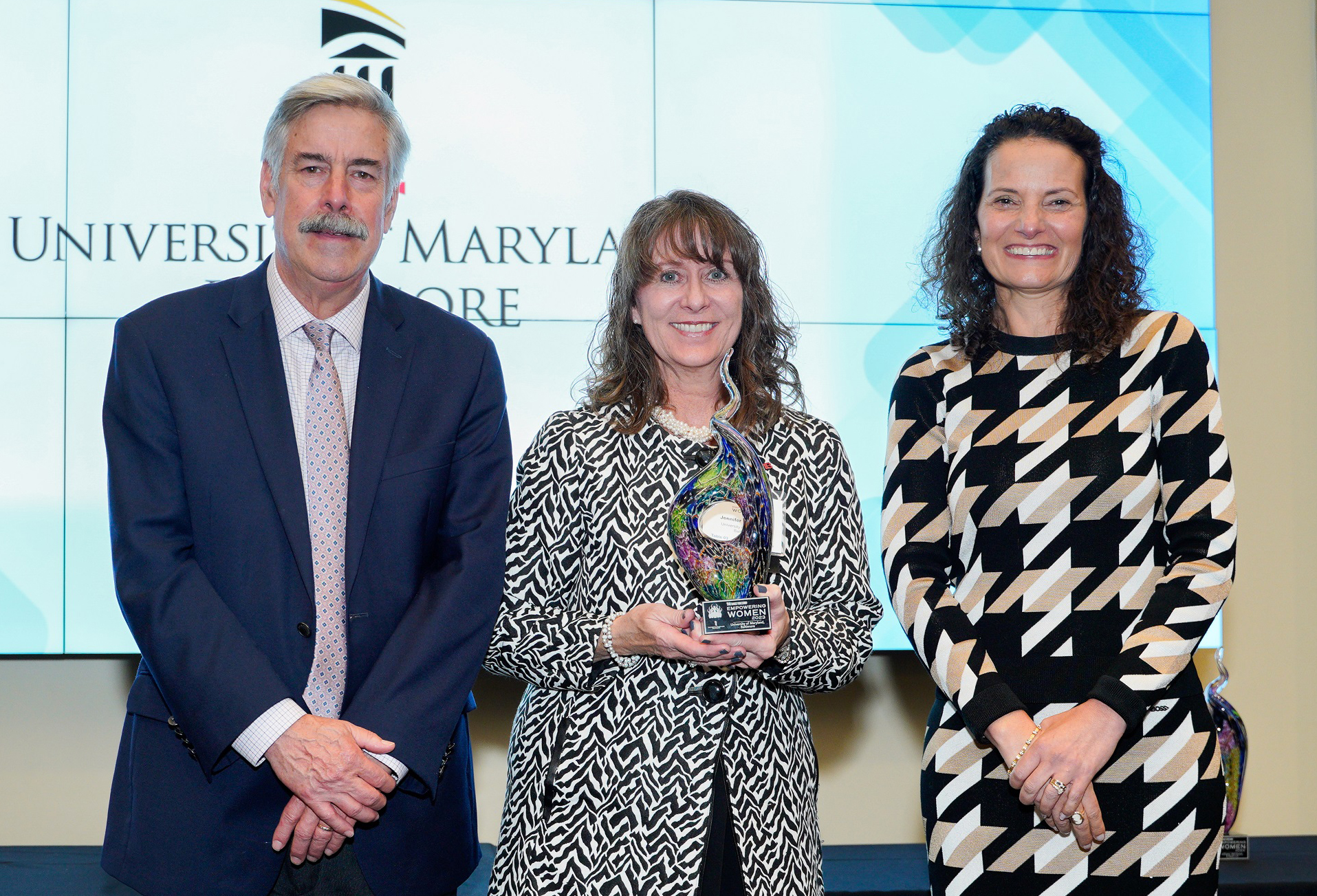 UMB’s Jennifer Litchman (center) accepts the University’s Empowering Women Award from Thomas Baden Jr. (left) and Suzanne Fischer-Huettner of “The Daily Record.”
