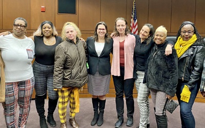 Leigh Goodmark (center wearing black), the Clinical Law Program’s co-director, poses with clients in the Maryland Carey Law Moot Courtroom.  