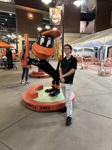 Benjamin standing by an Orioles statue at an Orioles game. 