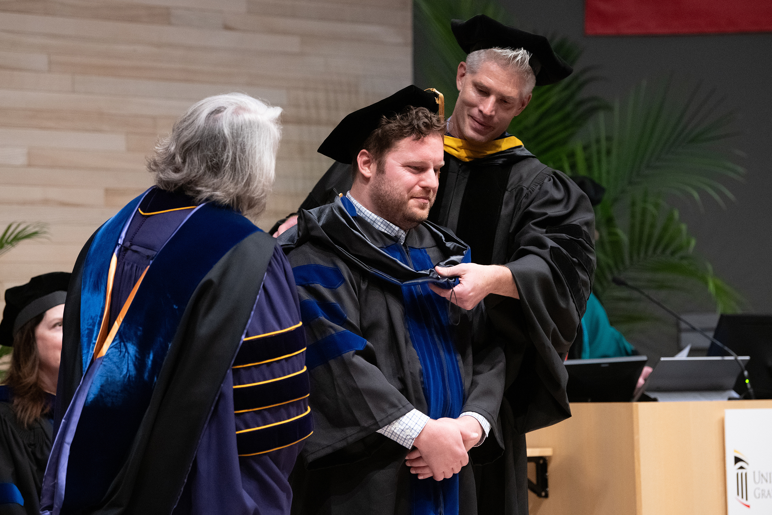 PhD graduate Todd Becker receives his hood from faculty mentor John Cagle, PhD, during the 2024 Graduate School Hooding Ceremony. 