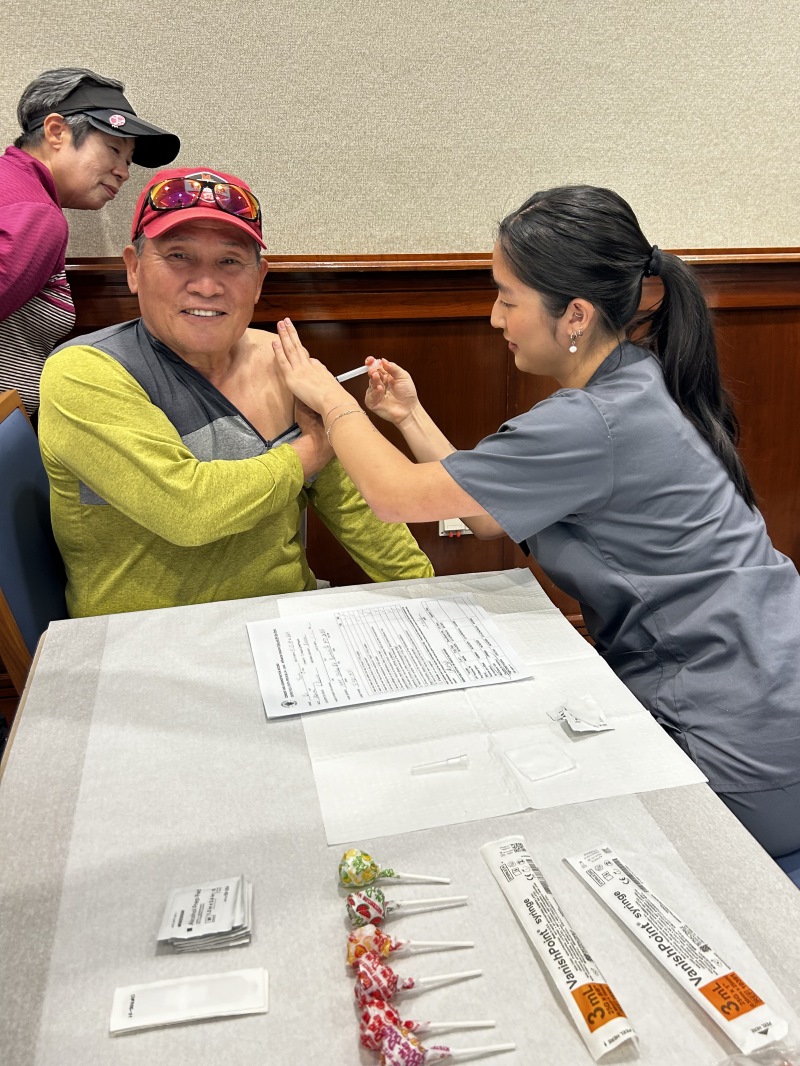 BSN student Madelyn Yi administering the flu vaccione to her grandfather