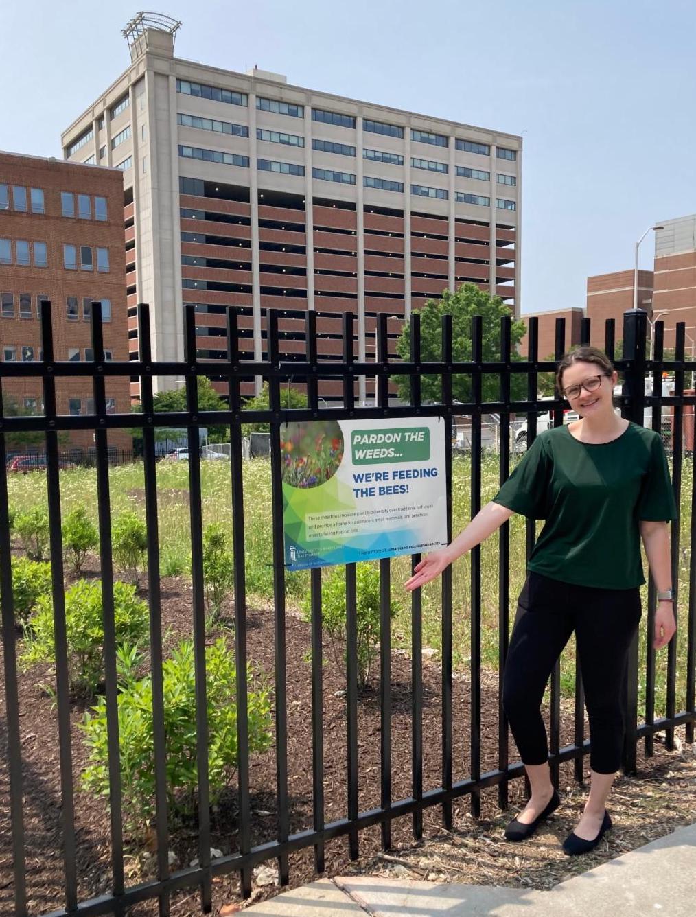 Sustainability Director standing in front of ecological landscaping sign.