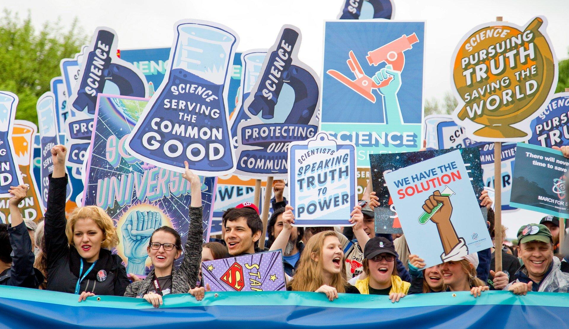 Group of demonstrators holding signs about the the value of science