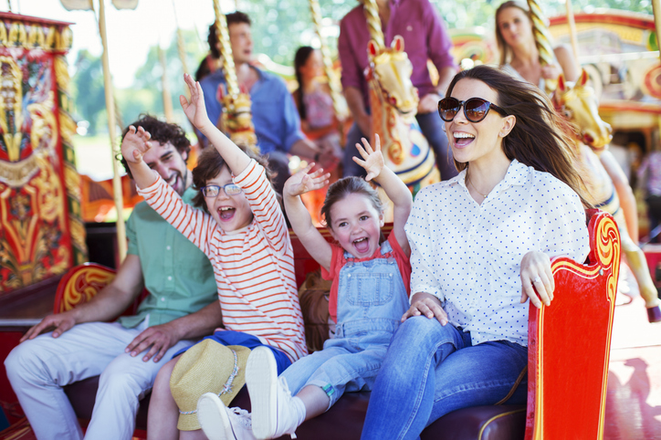 Happy, energetic, smiling family on amusement park ride - colors are vibrant, mood is happy and fun