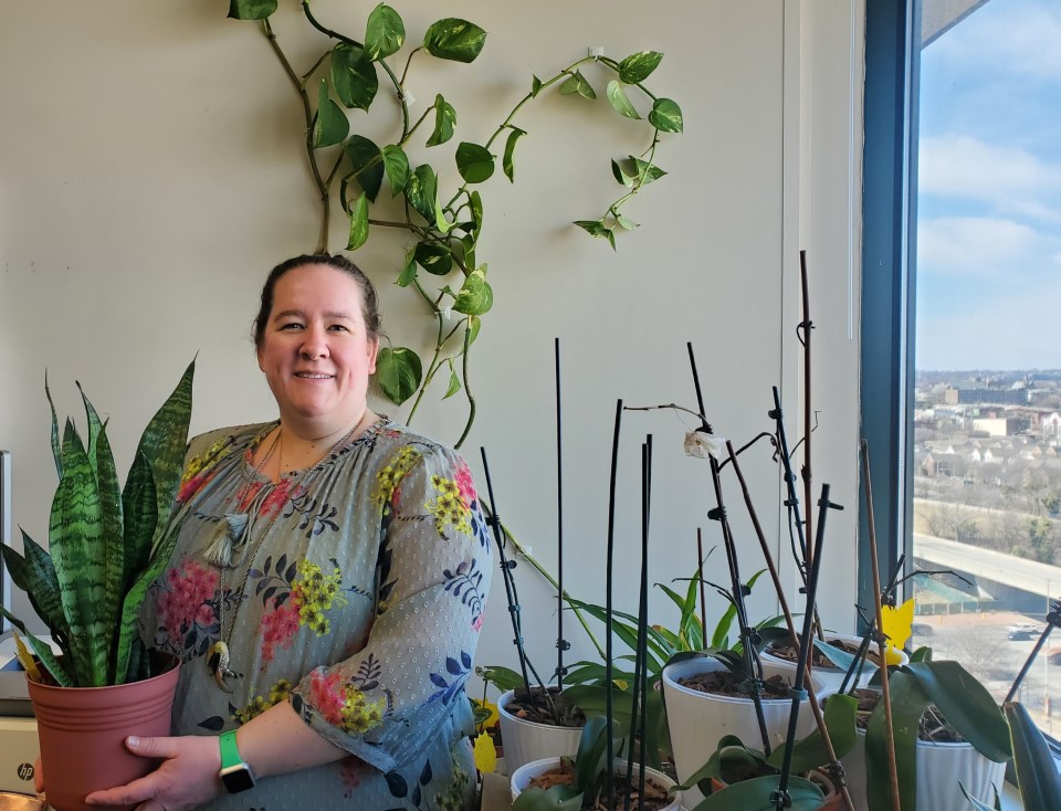 Victoria Meadows stands tall amidst a sea of green cultivated in her office. 