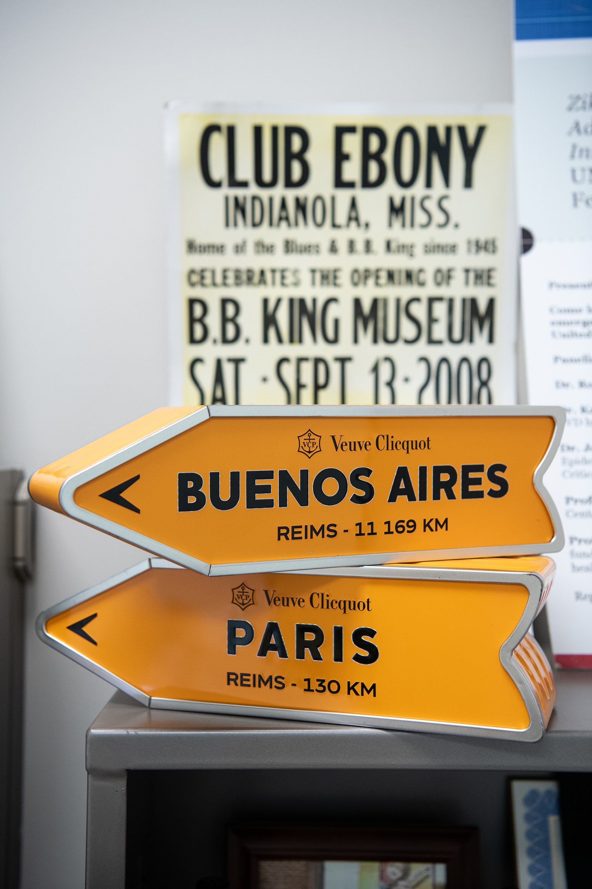 The two metal Veuve Clicquot Champagne containers that look like directional signs pointing to Buenos Aires and Paris sit on Virginia Rowthorn's desk