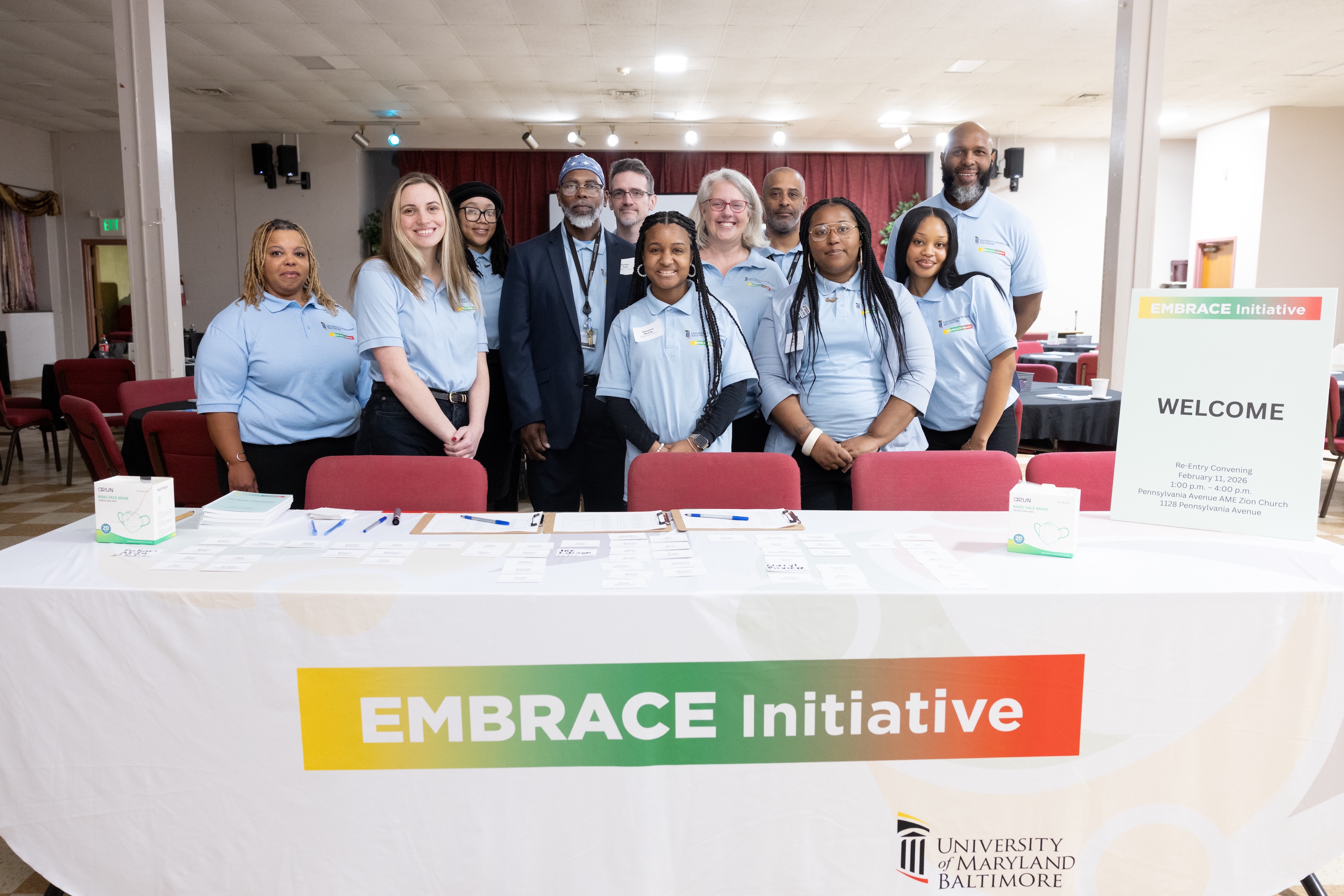 EMBRACE employees pose in front of a table that says EMBRACE Initiative