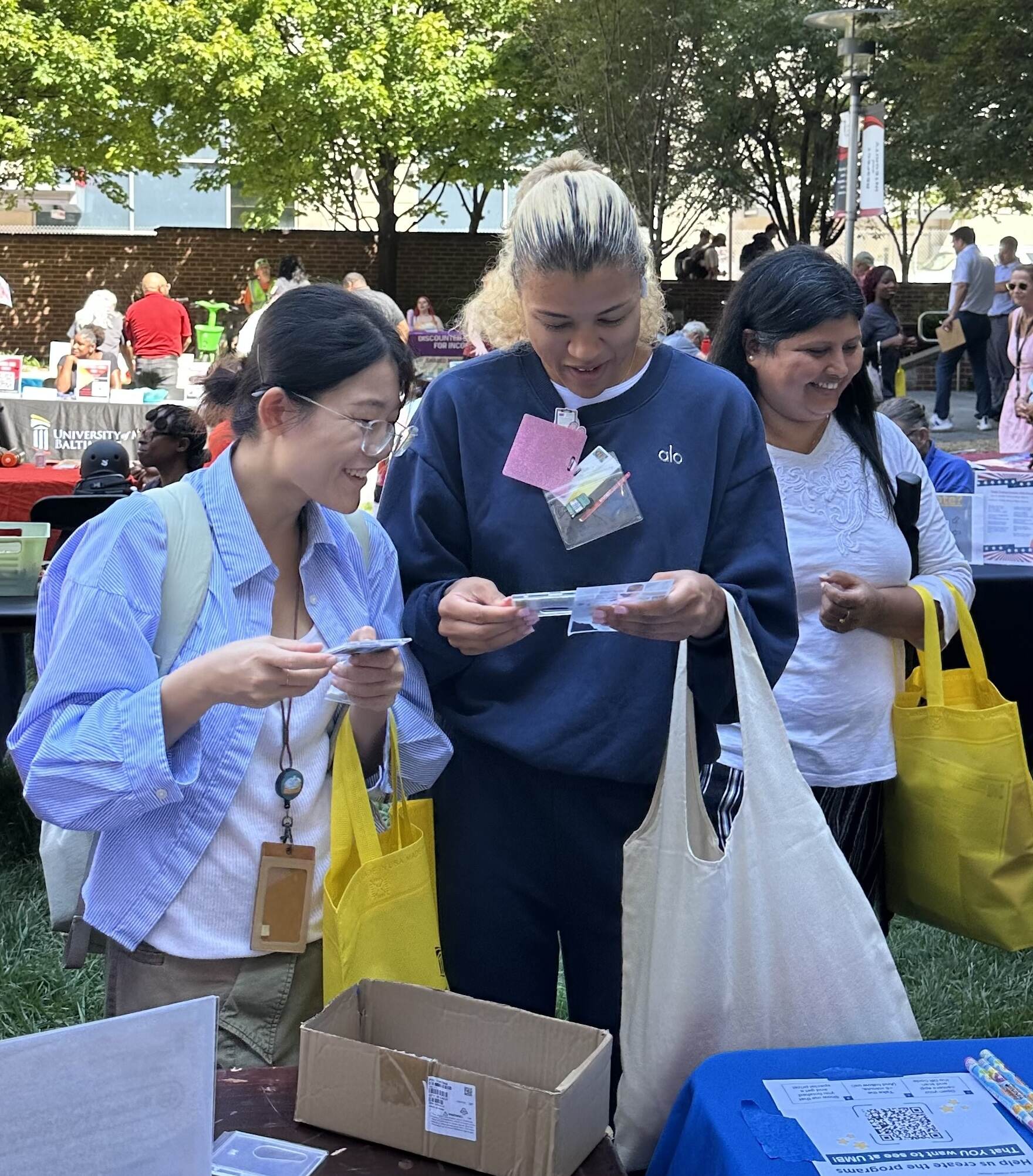 Two female students smile while admiring a OneCard badge holder that they decorated as part of an activity at the Campus Involvement Fair on the School of Nursing Lawn.