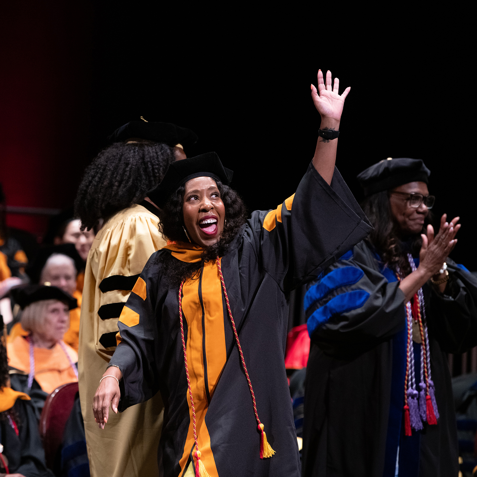 A graduate of the School of Nursing waves to the crowd at the Hippodrome