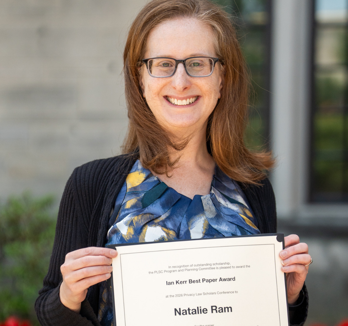 Natalie Ram standing outside smiling and holding a certificate