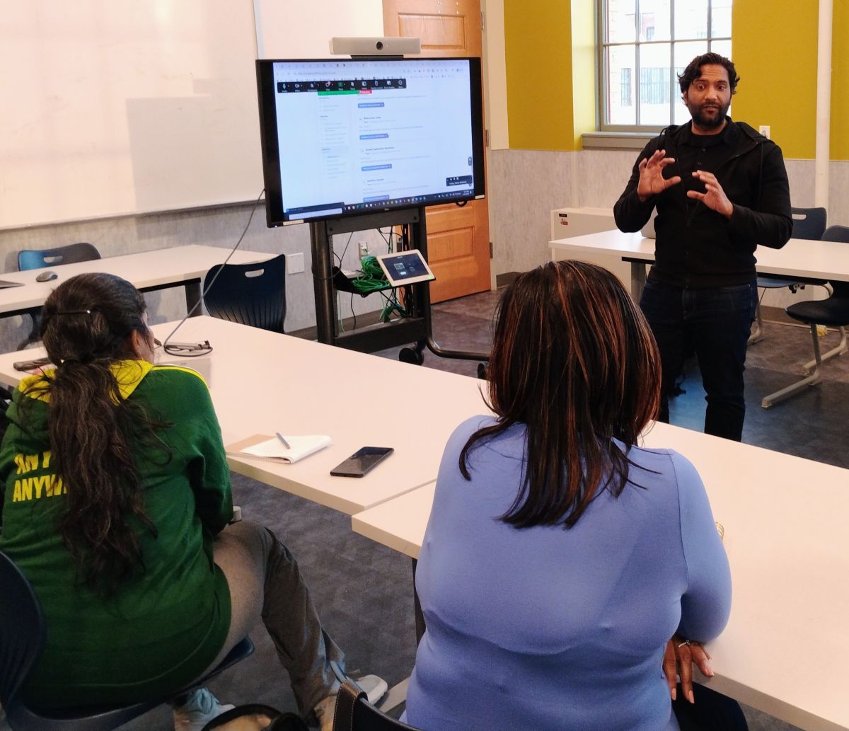 Rishan Mohamed, Founder and CEO of HiringCoach.AI, leading the Using AI in Your Job Search workshop. Two women are seated looking toward Rishan and away from the camera.