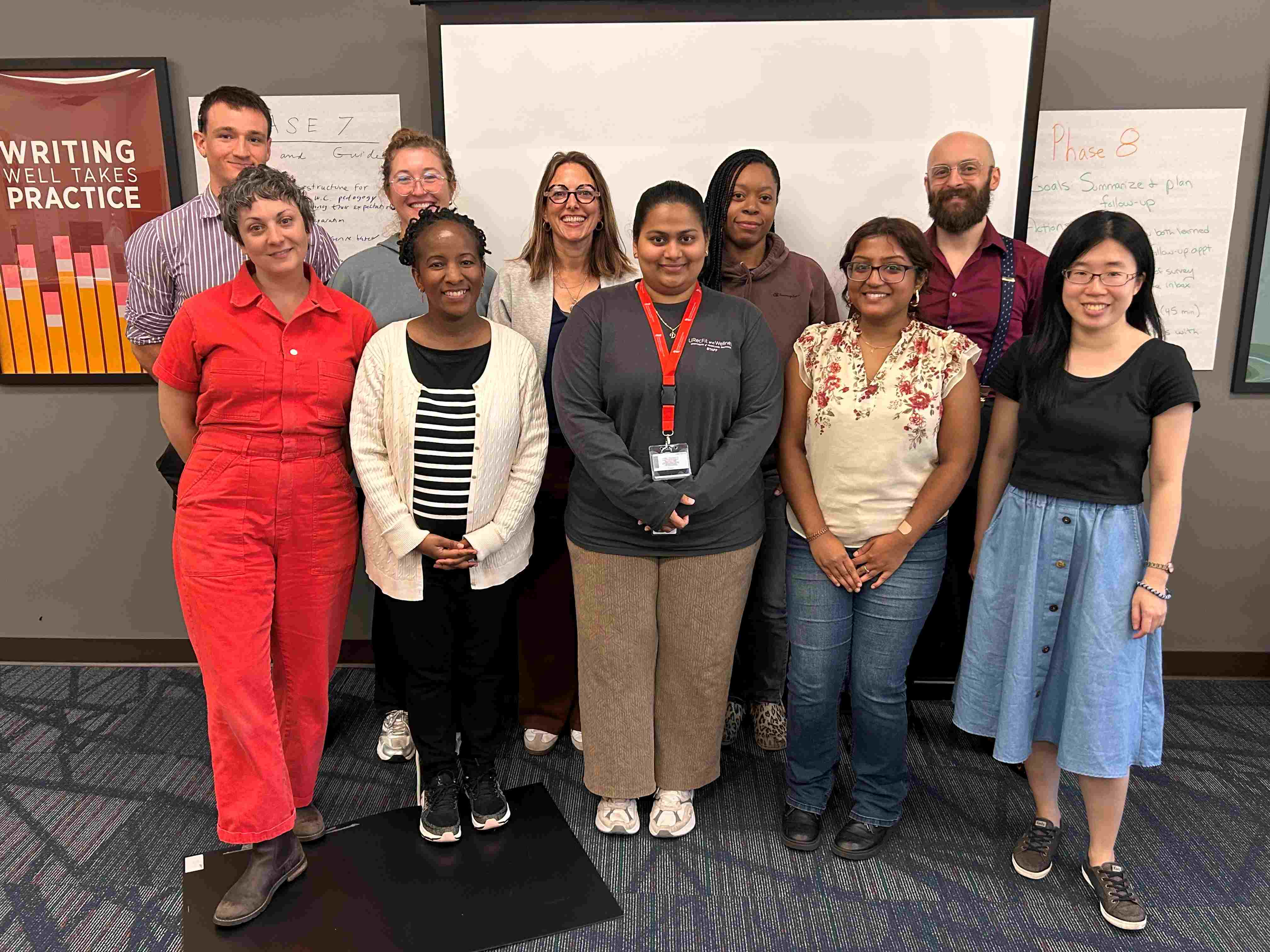 A group of diverse students posing in the UMB Writing Center.