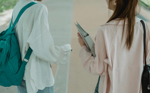 Two students talking and walking together on campus, representing peer connection and mentorship.