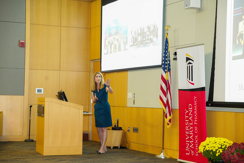 Dean Sarah Michel stands at a podium in a lecture hall and gestures to content on a large screen. 