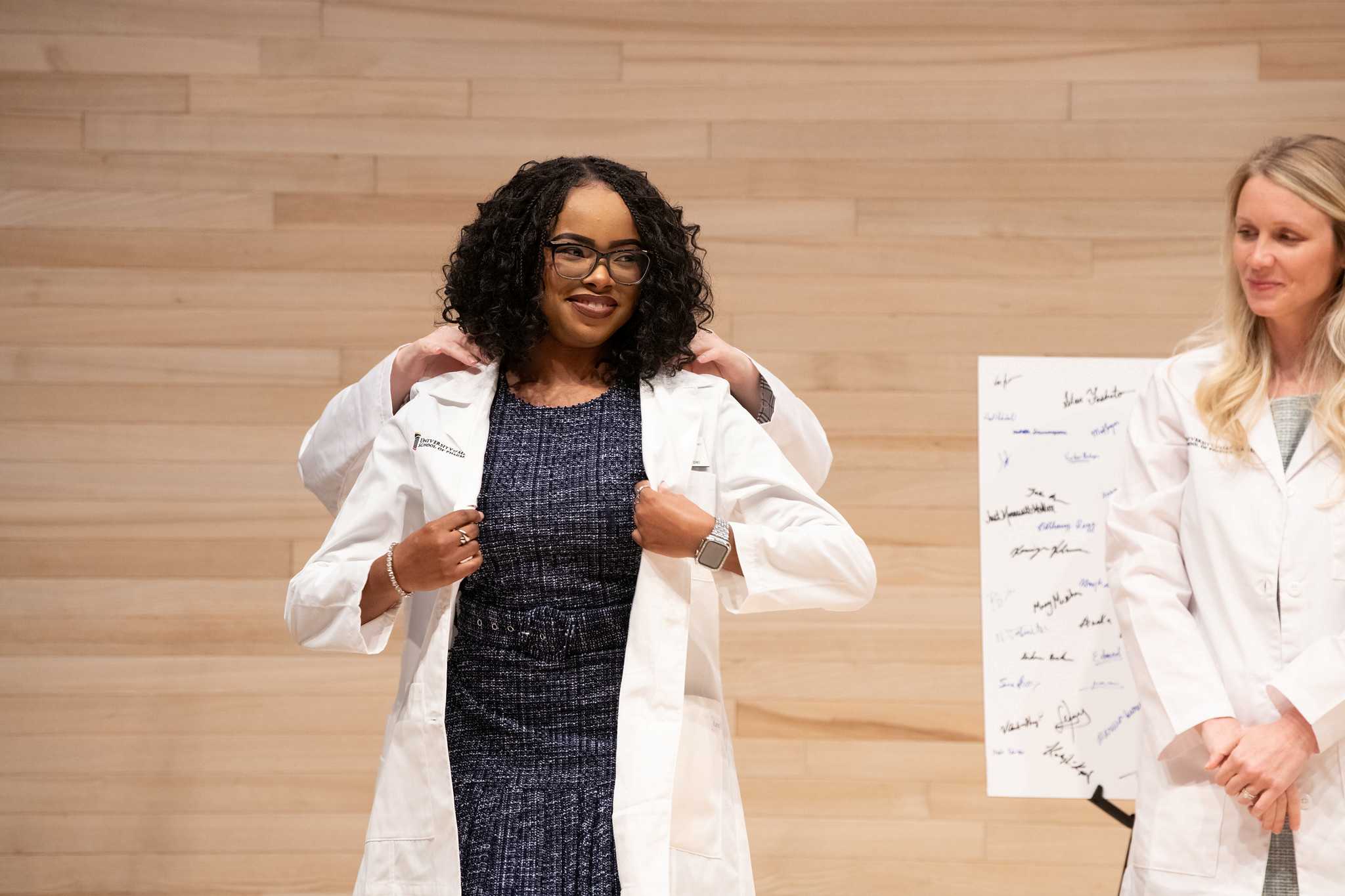 A student puts on her white coat at the school of pharmacy's annual white coat ceremony.