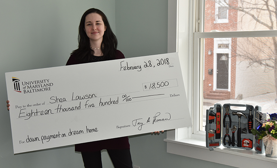 Shea Lawson, research project coordinator at the Brain and Tissue Bank at the University of Maryland School of Medicine, poses with a large check for her LNYW grant from UMB.