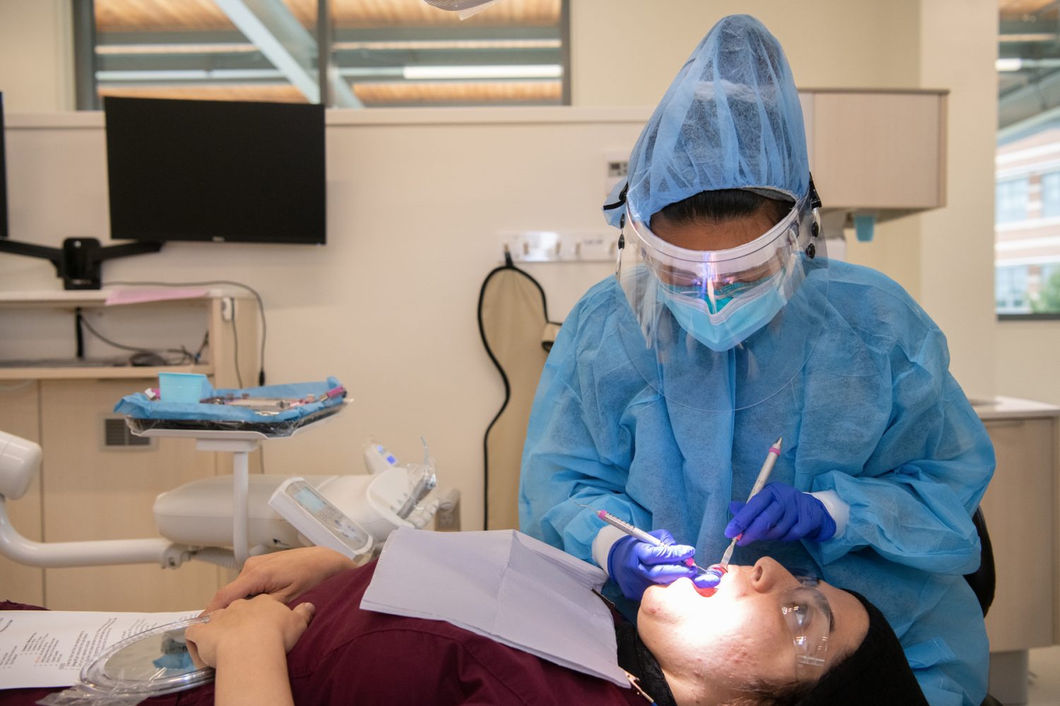 School of Dentistry student Phuang Hoang, Class of 2022, who is on the BS/MS dual-degree clinical dental hygiene leader track, examines a colleague at the Universities at Shady Grove.  