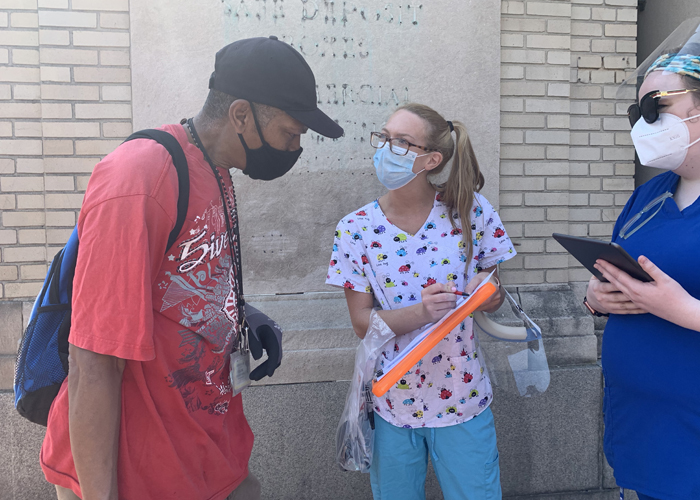 Maddie Boyes, RN (right), and Hayley Carper, RN (center), two students at the University of Maryland School of Nursing, help William Lipmann, a West Baltimore community member, get registered for a va