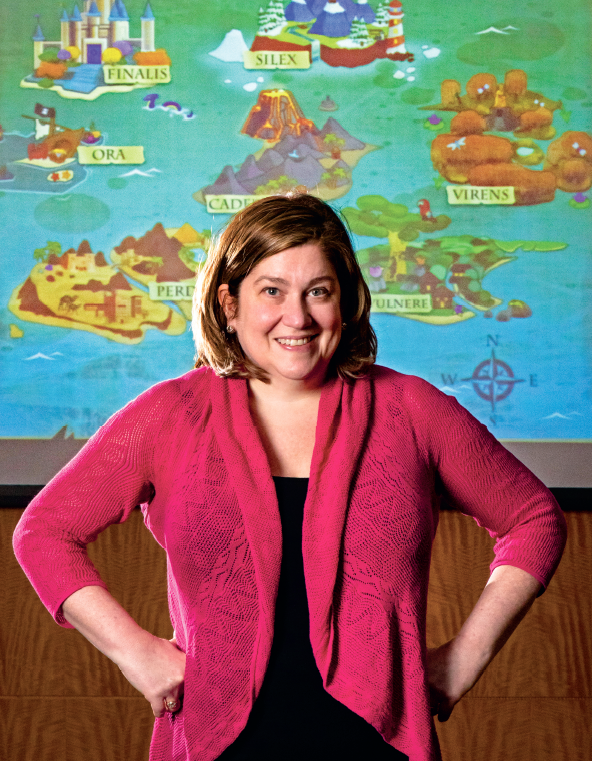 Stacy Brull stands in front of a screen showing the game she developed