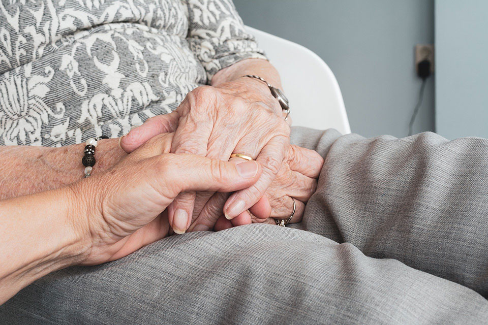 Caregiver holds patient's hand.