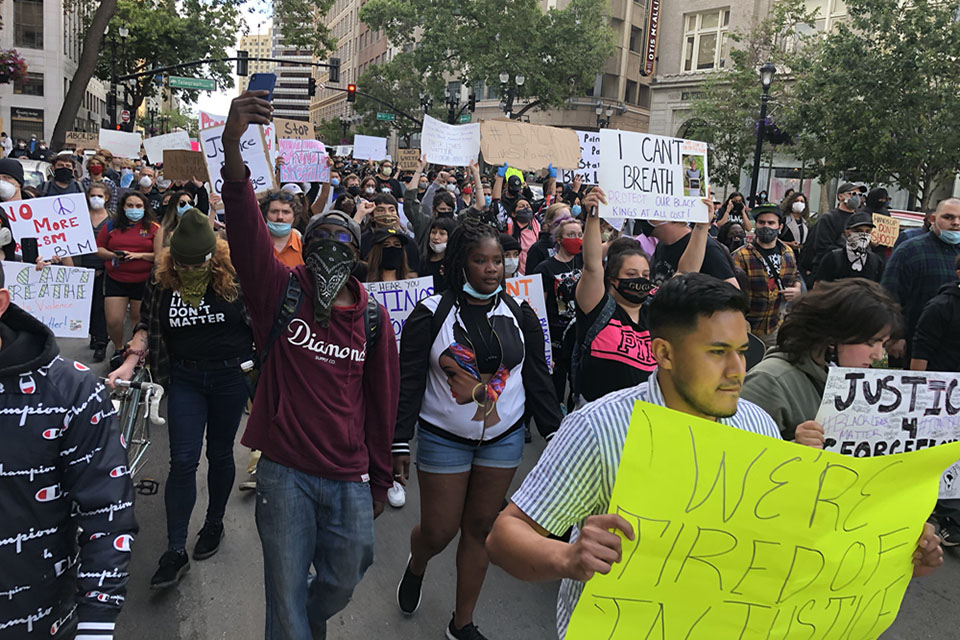Group of individuals march down a street in protest of the death of George Floyd.