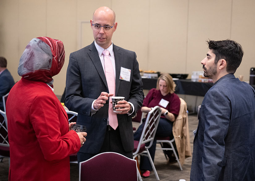 CHHS Executive Director Markus Rauschecker speaks to two participants at an event.