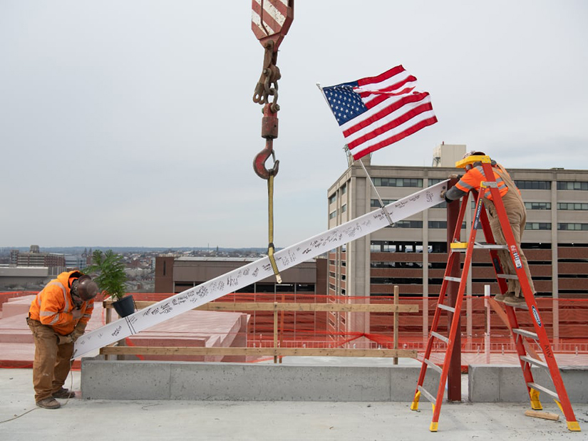 Workers maneuver the final beam at the topping-off ceremony for the new School of Social Work building.